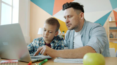 Father and son learning together on a laptop.