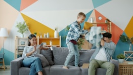 Family having a pillow fight on the couch.