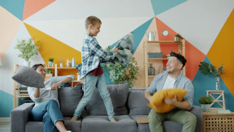 Family having a pillow fight on the couch.