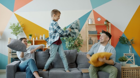 Family having a pillow fight on the couch.