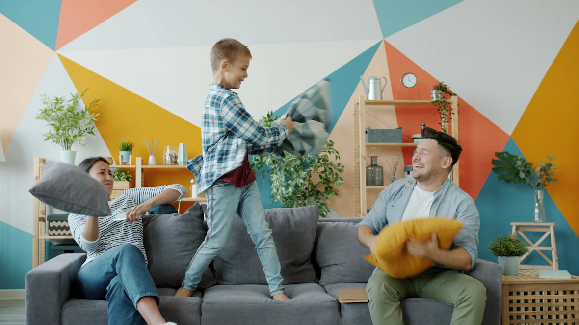 Family having a pillow fight on the couch.