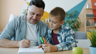 Father and son drawing together at a table.