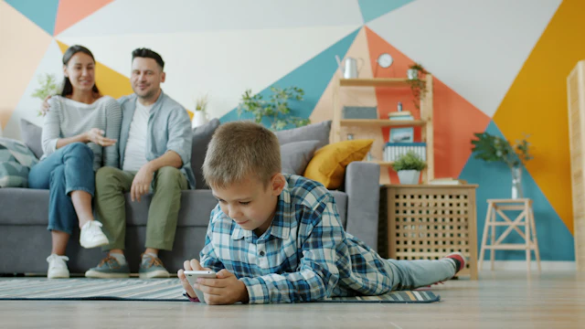 Niño usando un móvil mientras sus padres observan en el salón