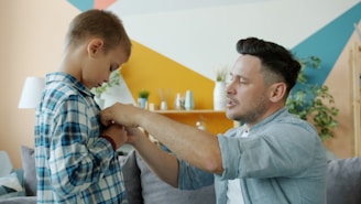 Father helps his son button his shirt.