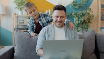 Father and son looking at laptop on couch