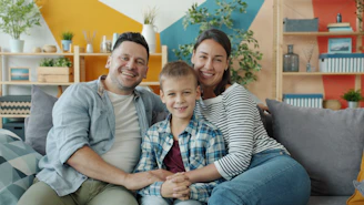 A happy family of three sitting on a couch.
