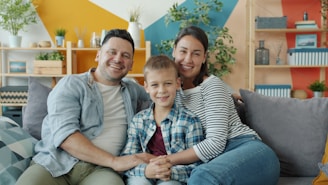 A happy family of three sitting on a couch.