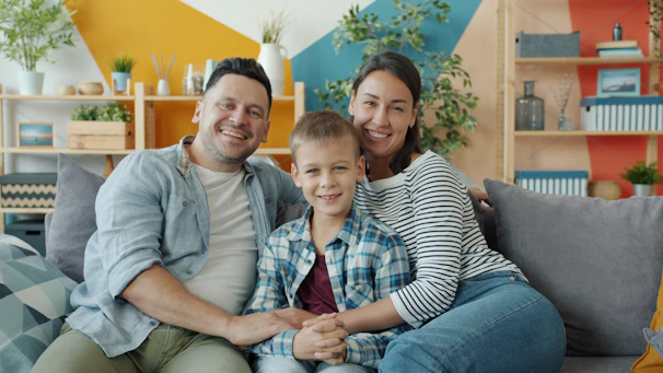A happy family of three sitting on a couch.