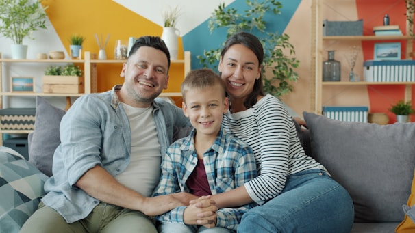 A happy family of three sitting on a couch.