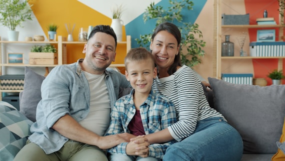 A happy family of three sitting on a couch.