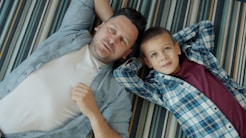 Father and son lying on striped blanket
