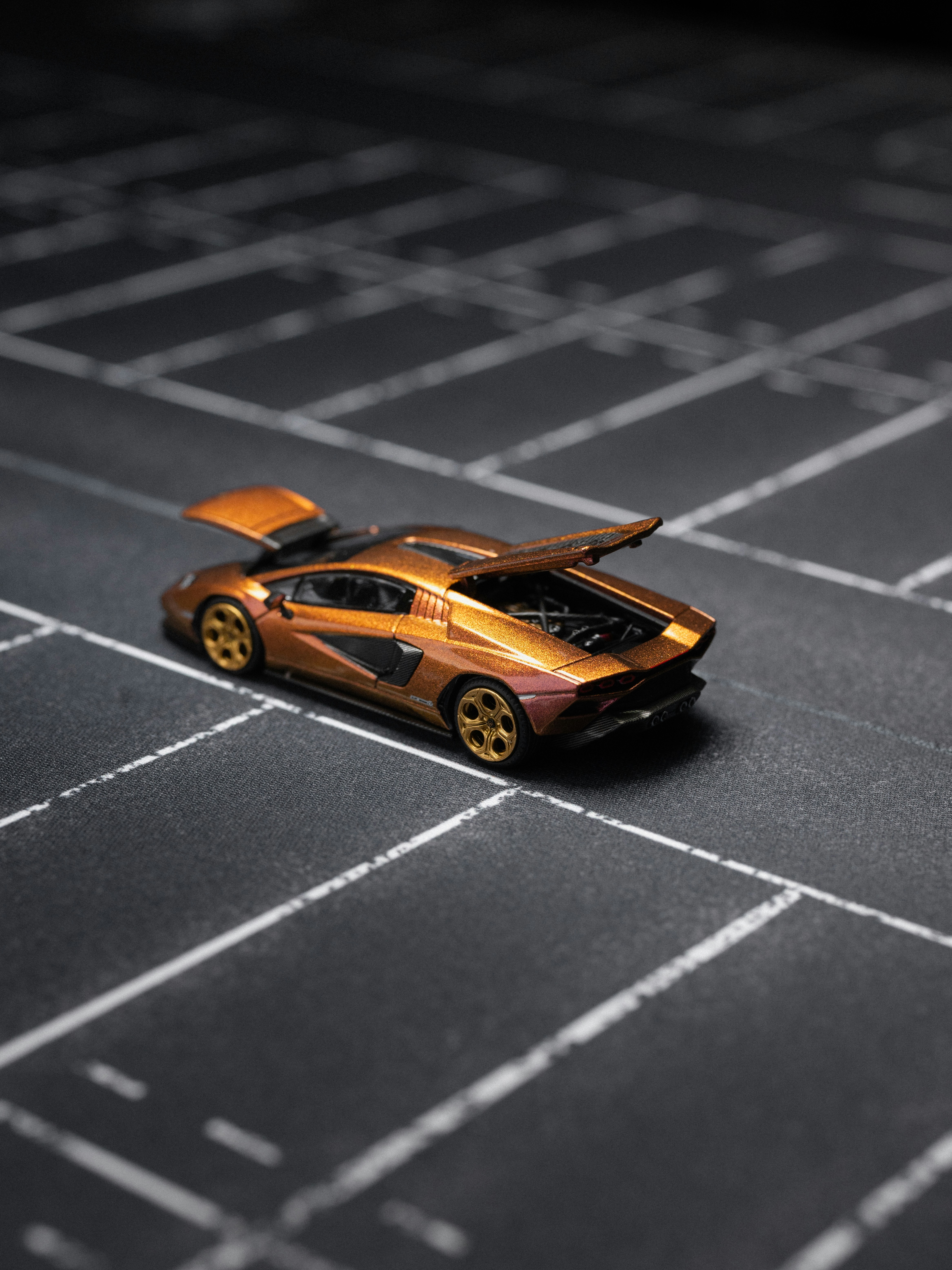 A miniature bronze sports car with open hood and trunk.