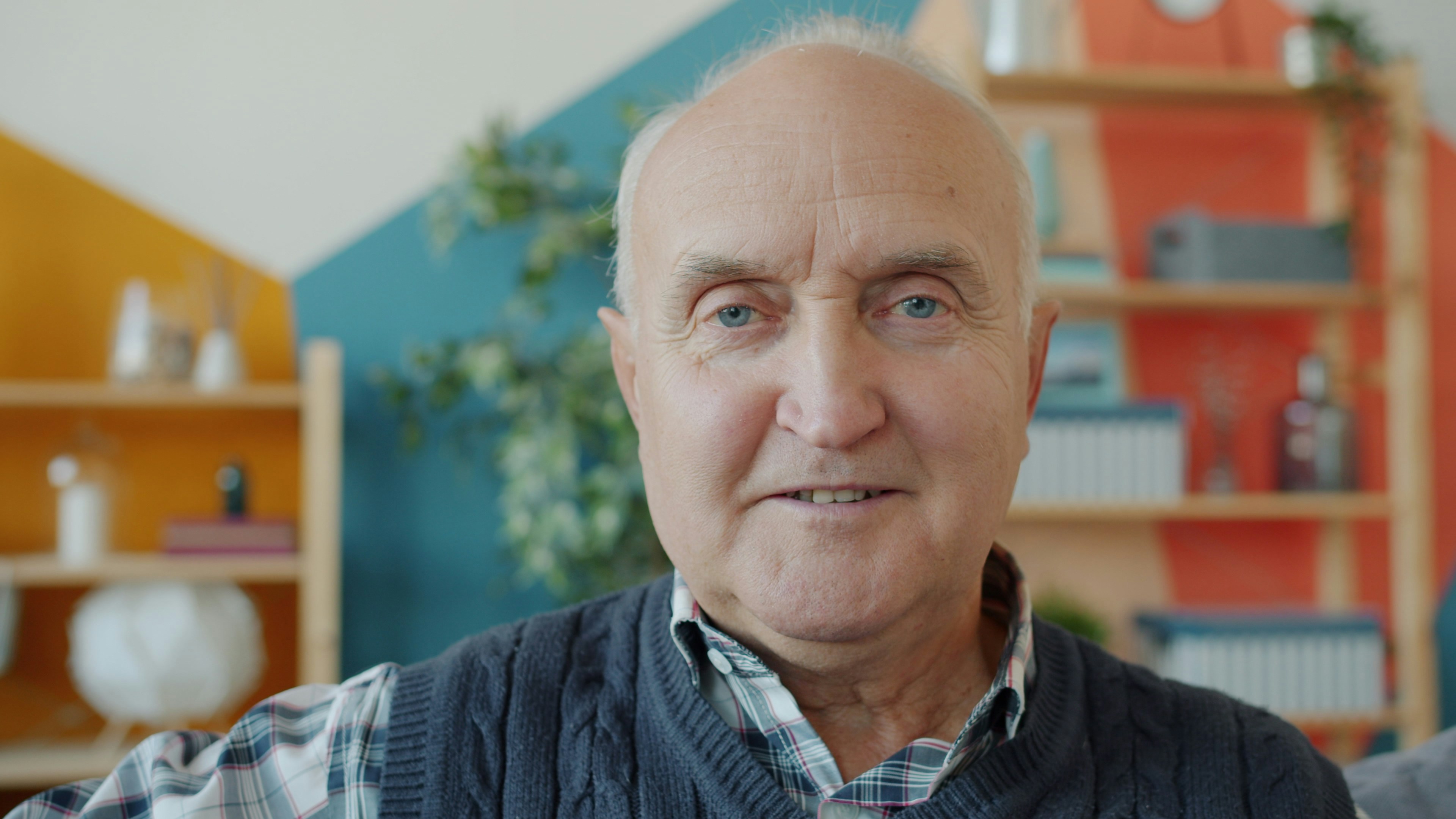 Elderly man with a warm smile in a living room.