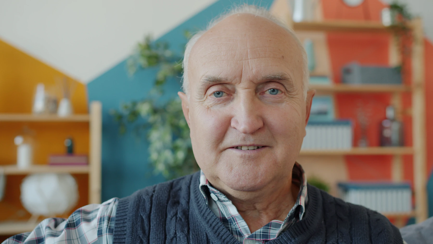 Older man smiling while seated in a bright living room