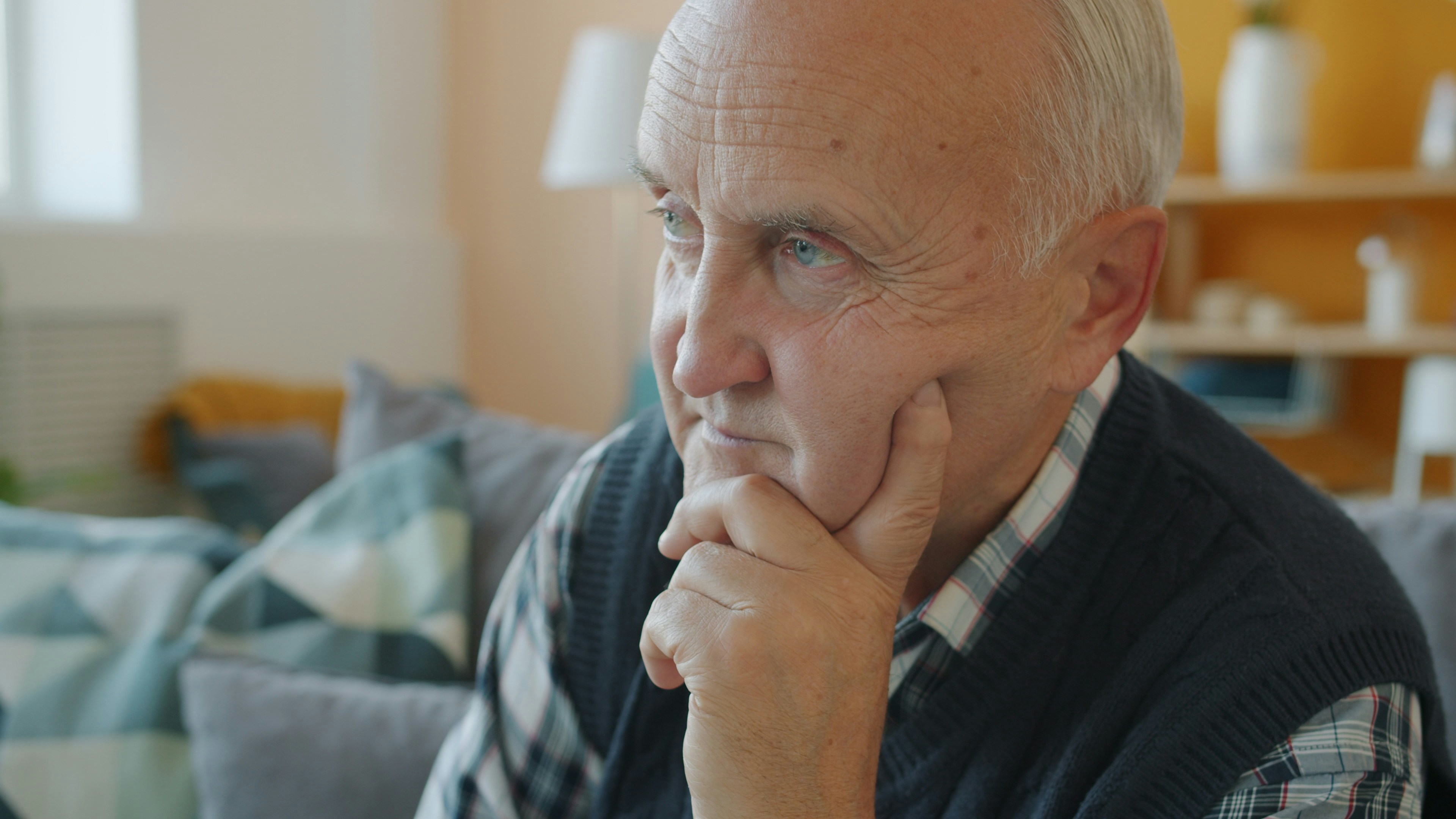 Elderly man with hand on chin, deep in thought.