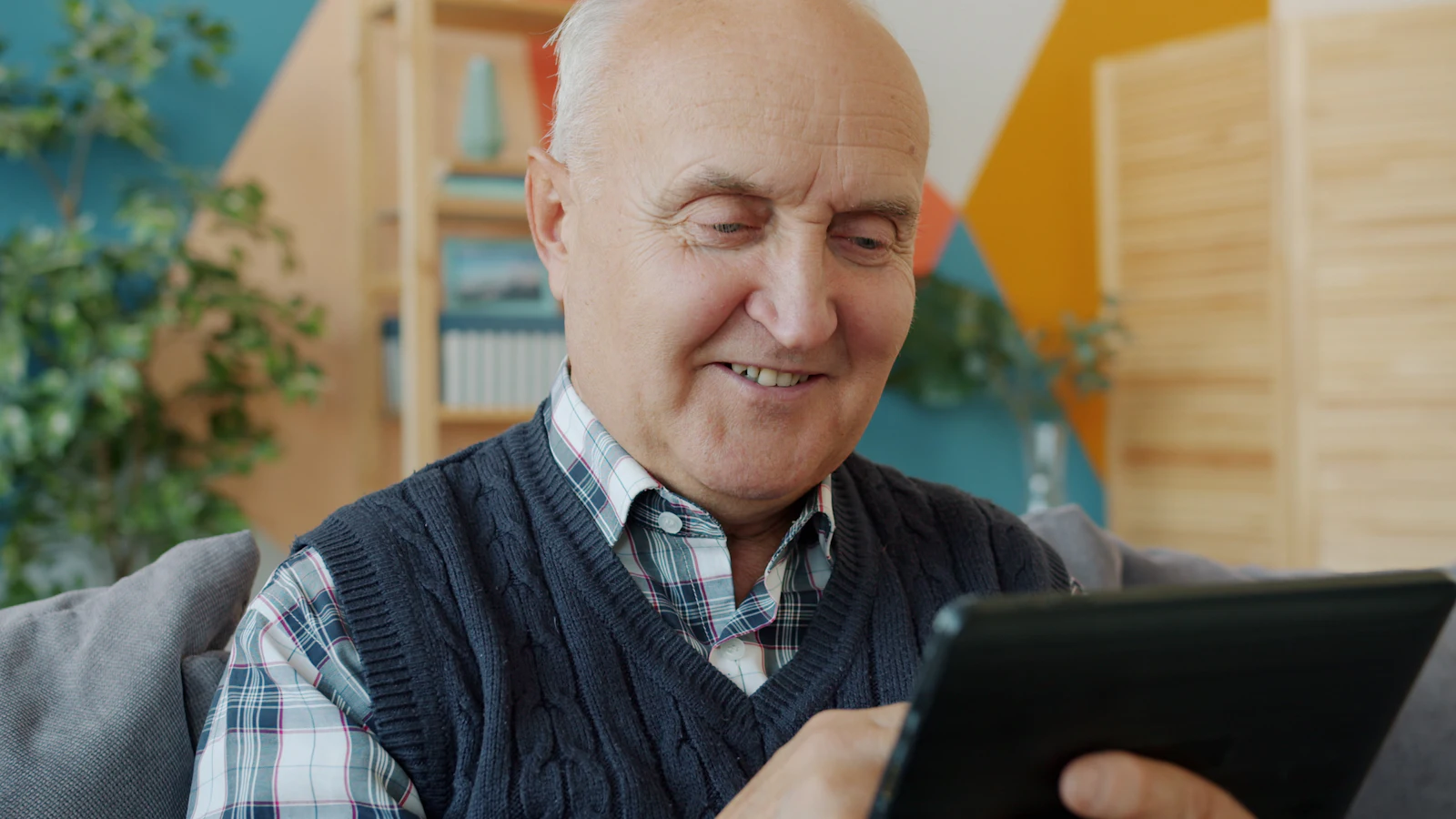 A smiling senior man using a tablet at home