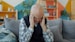 Elderly man holding head in discomfort on couch