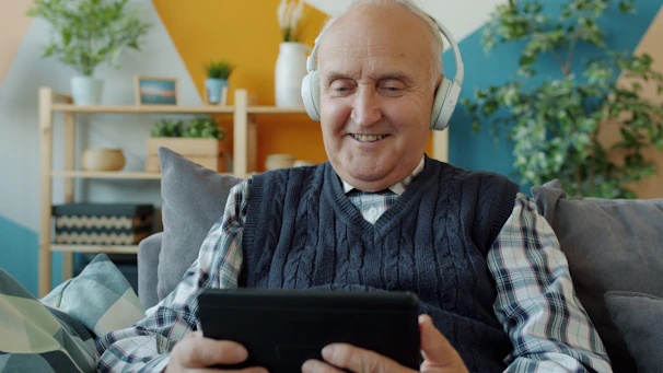 Elderly man with headphones using a tablet
