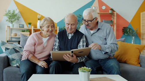 Three seniors looking at a photo album together.
