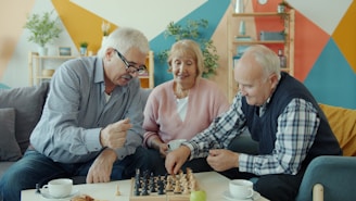 Three seniors playing chess together in a living room.