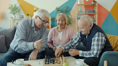 Three seniors playing chess together in a living room