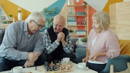 Seniors playing chess together on a sofa.