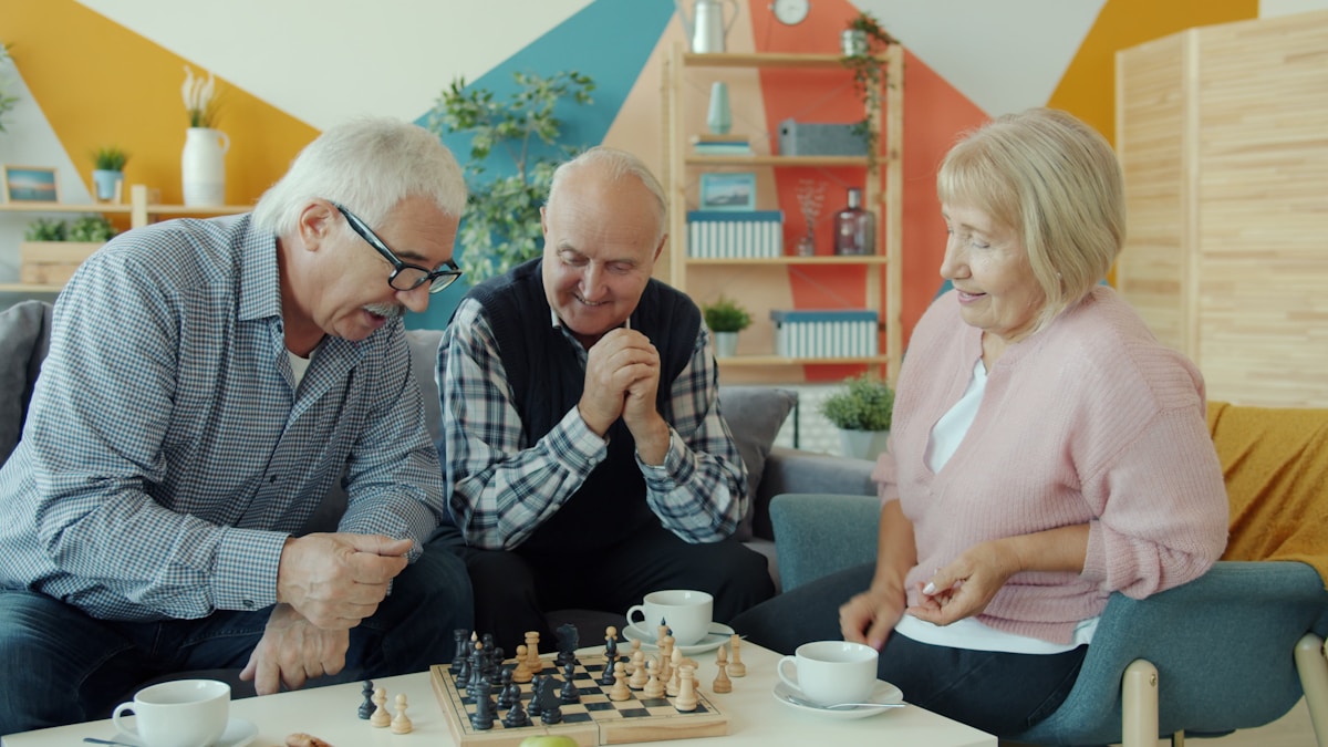 Seniors playing chess on a sofa at a volunteer appreciation event.