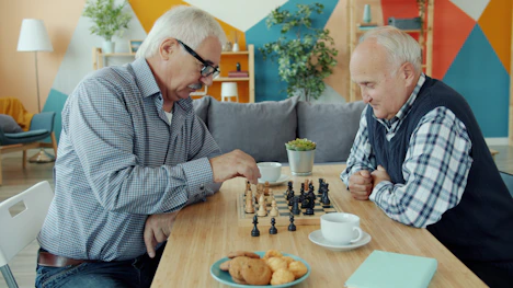 Two elderly men playing chess at a table.