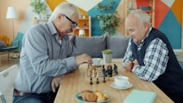 Two elderly men playing chess at a table.