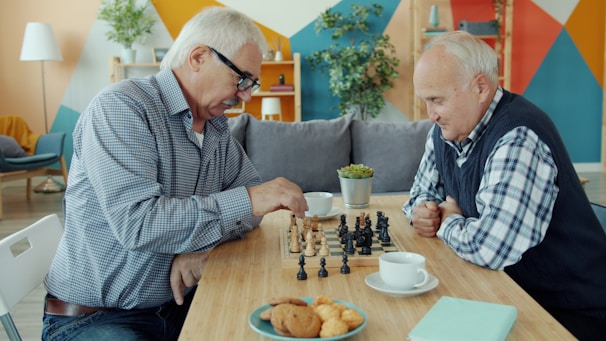 Two elderly men playing chess at a table.