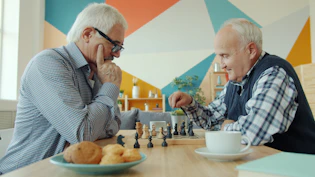 Two elderly men playing chess at a table