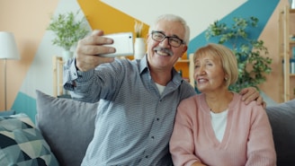 Elderly couple taking a selfie together on the couch.
