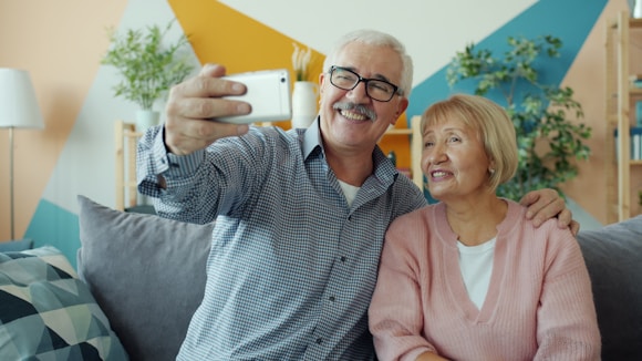 Elderly couple taking a selfie together on the couch.