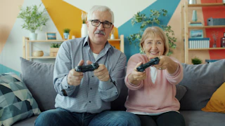Elderly couple playing video games together on couch