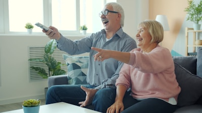 Elderly couple laughing while watching television