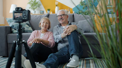 Elderly couple smiling at camera in-home video camera setup