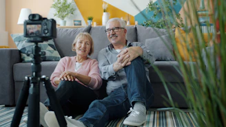 Elderly couple smiling at camera in-home video camera setup