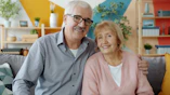 Elderly couple smiling together on a couch.