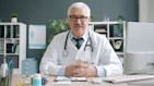 Elderly doctor in white coat with stethoscope at desk