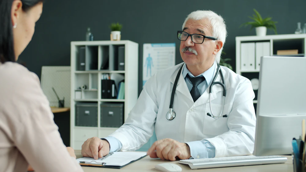 Doctor conversando con una paciente en un consultorio moderno