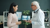 Doctor shows patient medical scan on tablet.