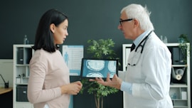 Doctor shows patient medical scan on tablet.