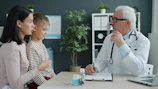 Doctor talking to mother and child at desk.