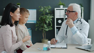 Doctor talking to mother and child at desk.