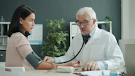 Doctor checks patient's blood pressure with stethoscope.