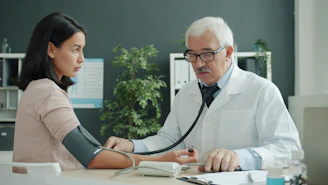 Doctor checks patient's blood pressure with stethoscope.