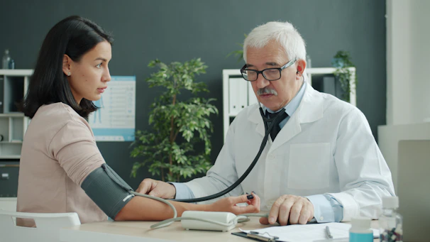 Doctor checks patient's blood pressure with stethoscope.