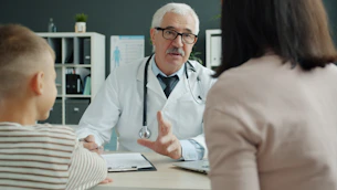 Doctor consults with mother and child in office.