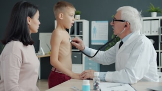 Doctor examines a young boy's chest with stethoscope.