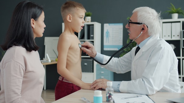 Doctor examines a young boy's chest with stethoscope.